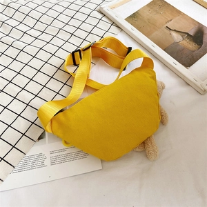 Sac bandoulière en toile jaune avec pendentif ours en peluche sur fond blanc épuré
