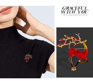 Detail shot of a red enamel reindeer brooch with golden antlers shown on a model