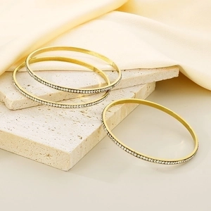 Detailed view of three gold-plated titanium bangles with sparkling zircon inlay