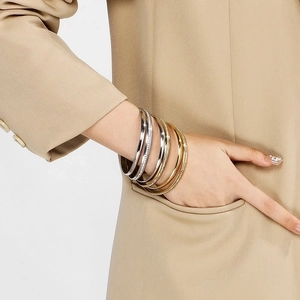 Detail of layered gold and silver stainless steel bangles with pave-set zircons