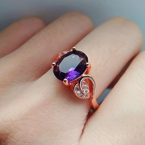 Rose gold ring featuring a large oval purple amethyst gemstone with leafy side accents