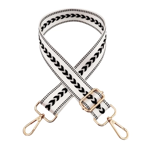 Macro detail of adjustable black and white chevron nylon strap with gold metal hooks