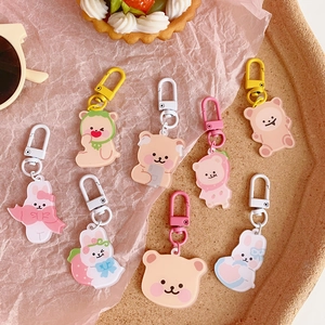 Set of eight cute acrylic bear and rabbit keychains on a decorative wooden tray