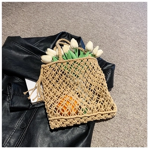 Handwoven beige crochet tote bag with hollow mesh design and fresh tulips on black jacket