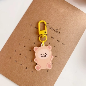 Macro shot of a pink acrylic cartoon bear keychain on a vintage calendar book background