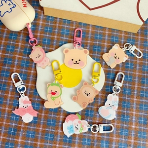 Flat lay of colorful acrylic cartoon bear and rabbit keychains on a checkered fabric