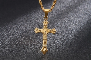 Macro detail of golden cross necklace showing Jesus figure and INRI engraving on twisted chain