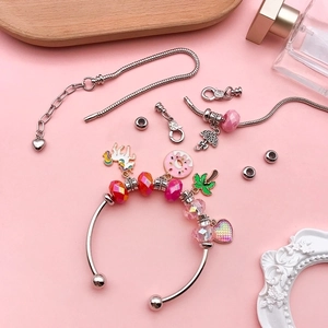 DIY charm bracelet set with silver bangles and colorful unicorn pendants on pink background