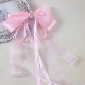 Detail of pink satin bow hair clip with organza streamers and pearl rhinestone centerpiece