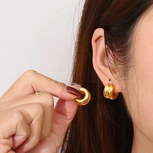 Macro detail of two-tone gold C-shaped ribbed earrings shown in a close-up on a model