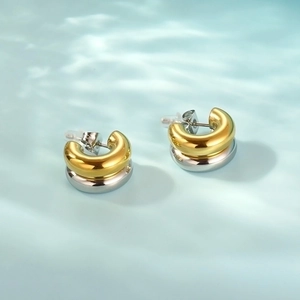 Detail of two-tone C-shaped hoop earrings with polished gold and silver finish