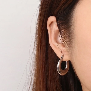 Close-up of a silver chunky oval hoop earring on model showing polished metallic texture