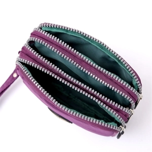 Detail view of purple nylon pouch featuring three zipper layers and dark green inner lining