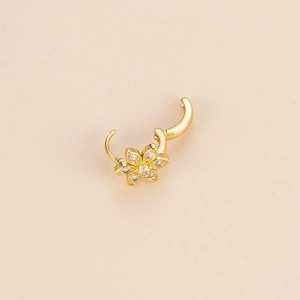Golden flower hoop earring with sparkling zircon petals on a neutral minimalist background
