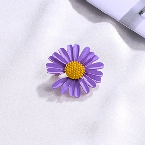 Detail of purple daisy brooch with yellow center on white satin background