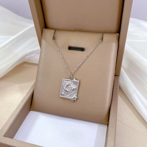 Detailed view of silver celestial pendant with sun and moon engravings in a gift box