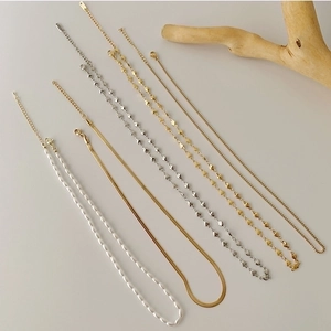 Layered gold and silver necklaces set featuring heart links, snake chains and pearl beads