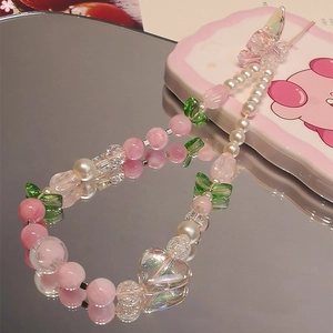Pink tulip floral beaded phone strap with heart and butterfly charms on reflective surface