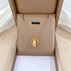 Detail of gold double-ring necklace with crystal accents resting on a jewelry box