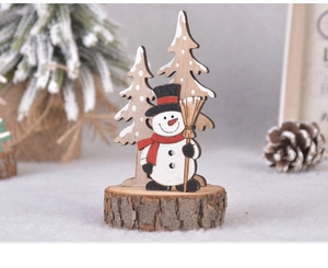 Detail of wooden snowman and pine trees ornaments on a natural wood slice base