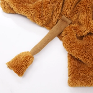 Macro view of brown plush fabric texture and decorative tassel detail on pet costume