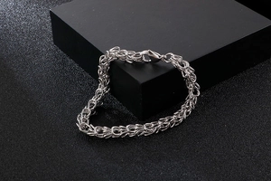 Detailed view of silver stainless steel chain bracelet with lobster clasp on black display
