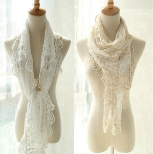 Detail of white lace scarf featuring intricate floral embroidery and delicate tassel edges