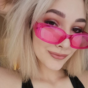 Close-up of stylish retro hip-hop sunglasses with pink translucent frames worn by model