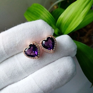 Macro shot of heart-shaped purple crystal earrings with rose gold plating and zircon