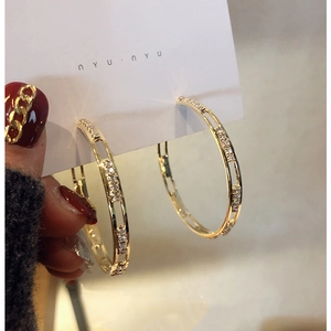 Close-up of gold hollow C-shaped earrings with rhinestones on white display card
