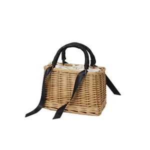 Handmade straw basket bag with black ribbon handle and drawstring liner in a 45-degree angle