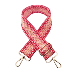 Detail of pink and orange geometric jacquard wide bag strap with gold metal swivel hooks