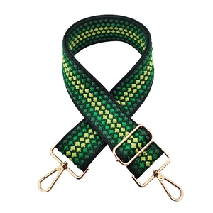 Detail of green and yellow geometric woven shoulder strap with gold metal lobster clasps
