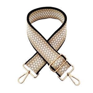 Detailed view of thick adjustable strap with geometric honeycomb pattern and gold metal hooks