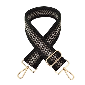 Detail of wide woven strap with black grey honeycomb pattern and gold metal buckles