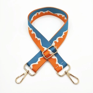 Detail of adjustable blue and orange jacquard bag strap with gold metal hooks and buckles