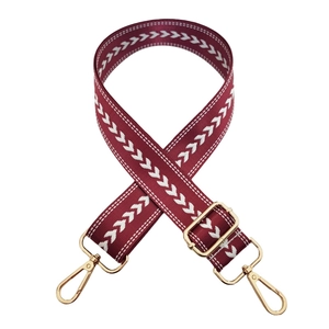 Detail of burgundy woven nylon strap with white arrow pattern and gold metal hardware