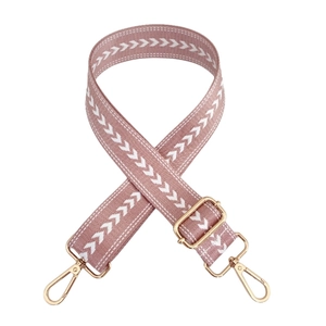 Close-up of pink nylon bag strap with white arrow pattern and gold metal hardware