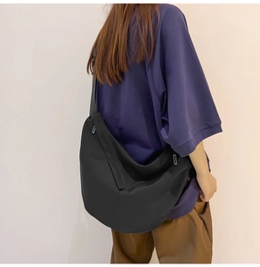 Male model wearing a large black nylon crossbody dumpling bag for casual daily use