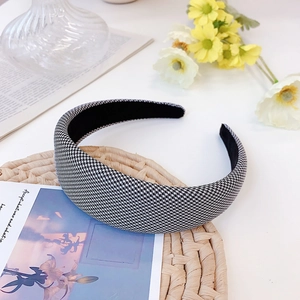 Detailed view of houndstooth headband on a rustic straw mat with elegant floral accents