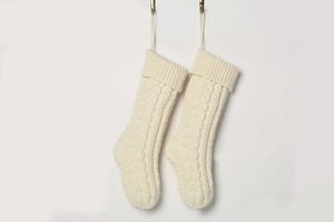 Close-up of cream-colored knitted Christmas stockings with classic cable knit pattern