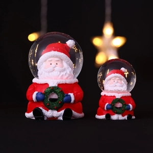 Boule à neige de Noël lumineuse avec Père Noël et base en résine sous lumières étoilées