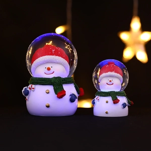 Boule à neige bonhomme de Noël avec lumières LED chaleureuses et bonnet rouge