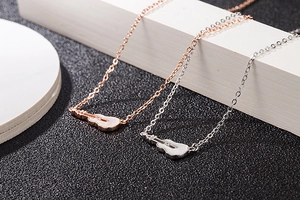 Close-up of guitar pendant necklaces in rose gold and silver with white shell inlay