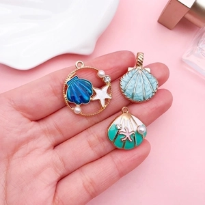 Three gradient colorful shell pendants with pearls and rhinestones on a pink background