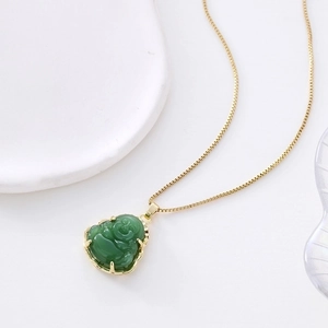 Elegant emerald green Buddha pendant necklace with gold chain on white porcelain plate