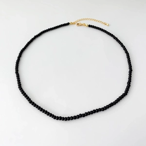 Detail of minimalist black agate beaded necklace with gold plated clasp and extension chain