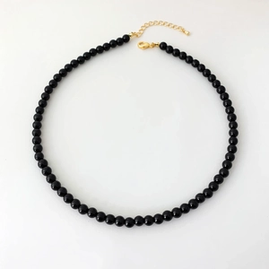 Detailed top view of black onyx beaded necklace with a golden lobster clasp and chain