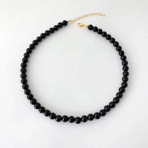 Polished black agate beads necklace with gold-plated lobster clasp on white background