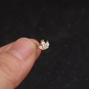 Macro detail of a golden crown-shaped labret stud with white marquise zircons